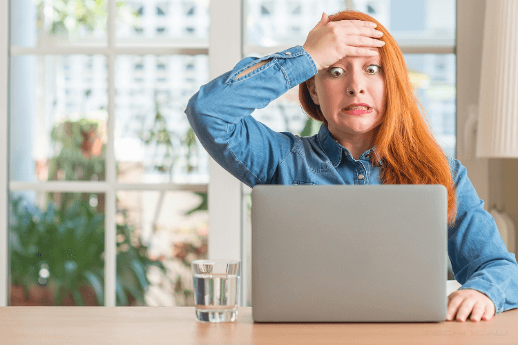 Girl Raised Eyebrows and Eyes in front of computer holding her right hand to head.