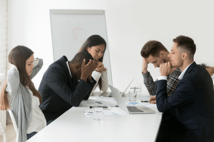 scene of meeting room with men and women, all seem stressed