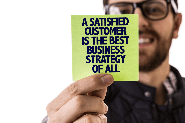 a man holding sticky note with text "a satisfied customer is the best business strategy of all