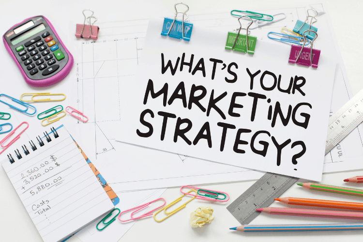 what is your marketing strategy ? written on white paper with stationary around it