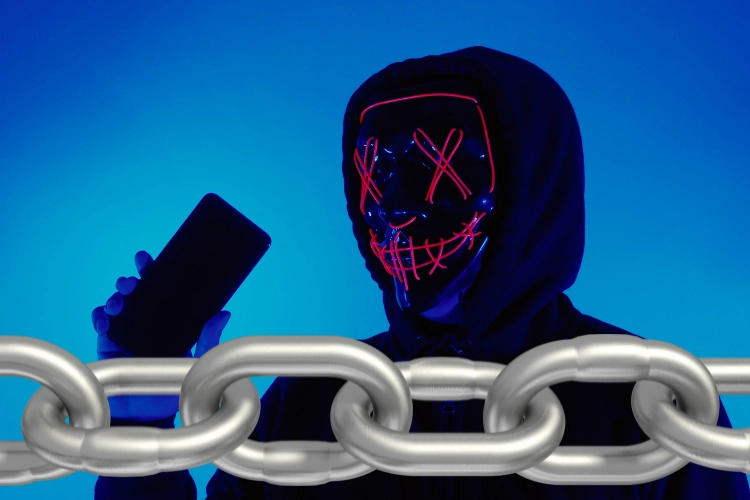 hacker with a red face lined mask holding phone.