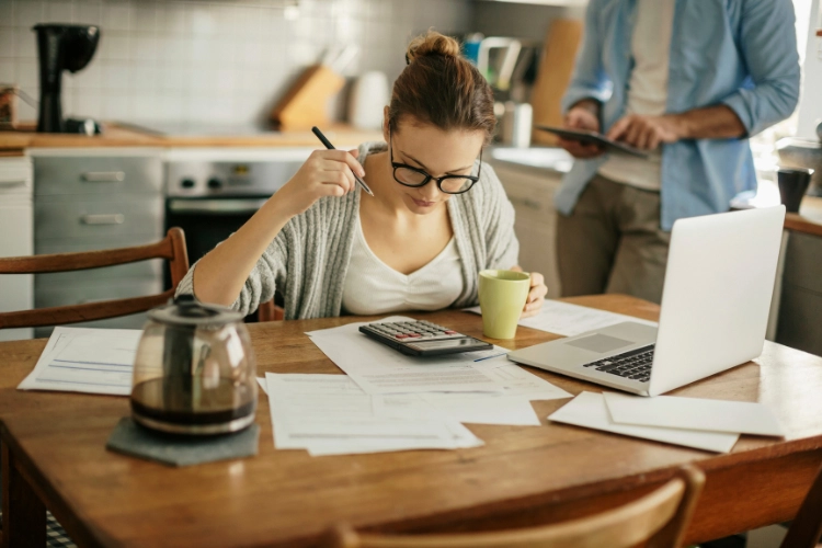 Girl Planning Budget with Calculator and Coffee and Laptop 