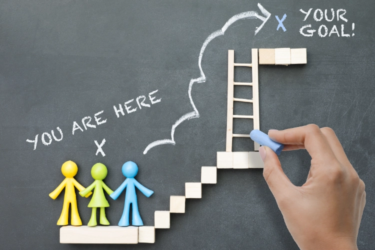 three human figurines are about to climb the stairs to reach their goal