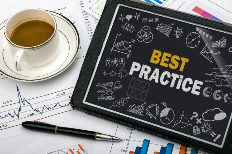 Tablet displaying "Best Practice" with graphs and doodles, surrounded by financial charts, a pen, and a coffee cup
