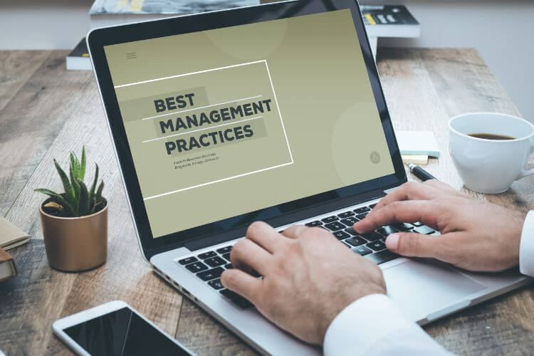 A person types on a laptop displaying "Best Management Practices" on a screen.